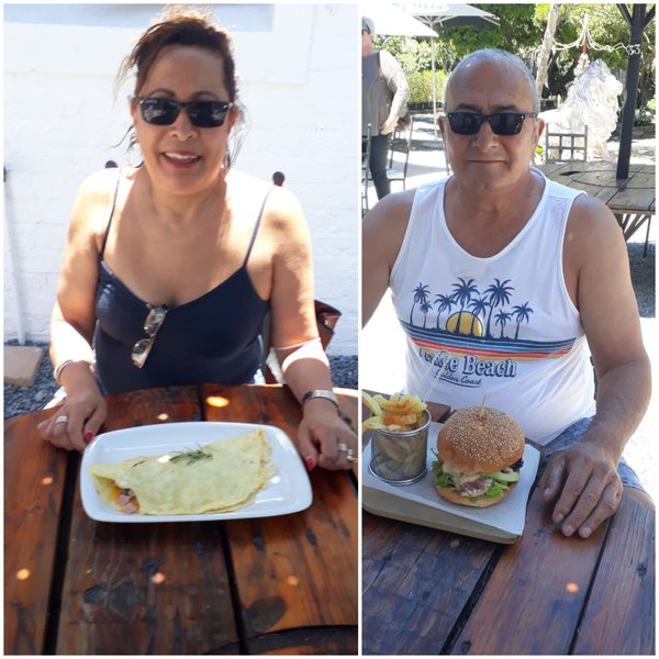 Joy and John at a café table, each smiling with a meal in front of them